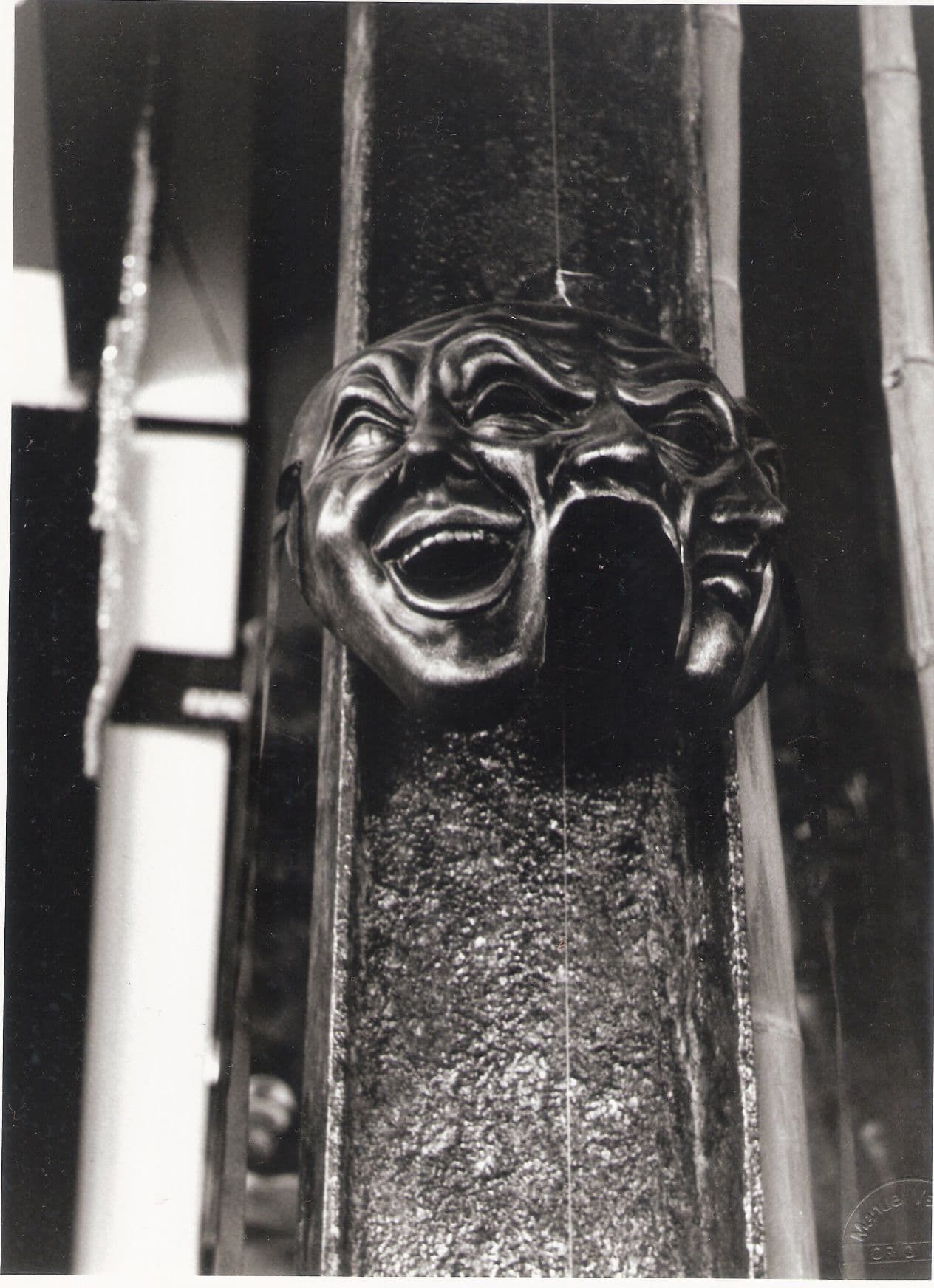 Máscara de teatro de bronce sobre una columna
