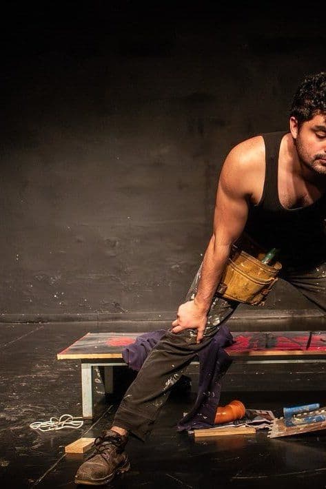 Un actor en musculosa sentado en un banco de madera, en Andamio